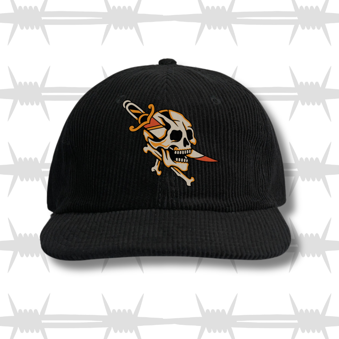 Dagger Front Cord Cap front image, shows a traditional style tattoo skull with a dagger through it, embroidered on the centre of a curved peak cap.