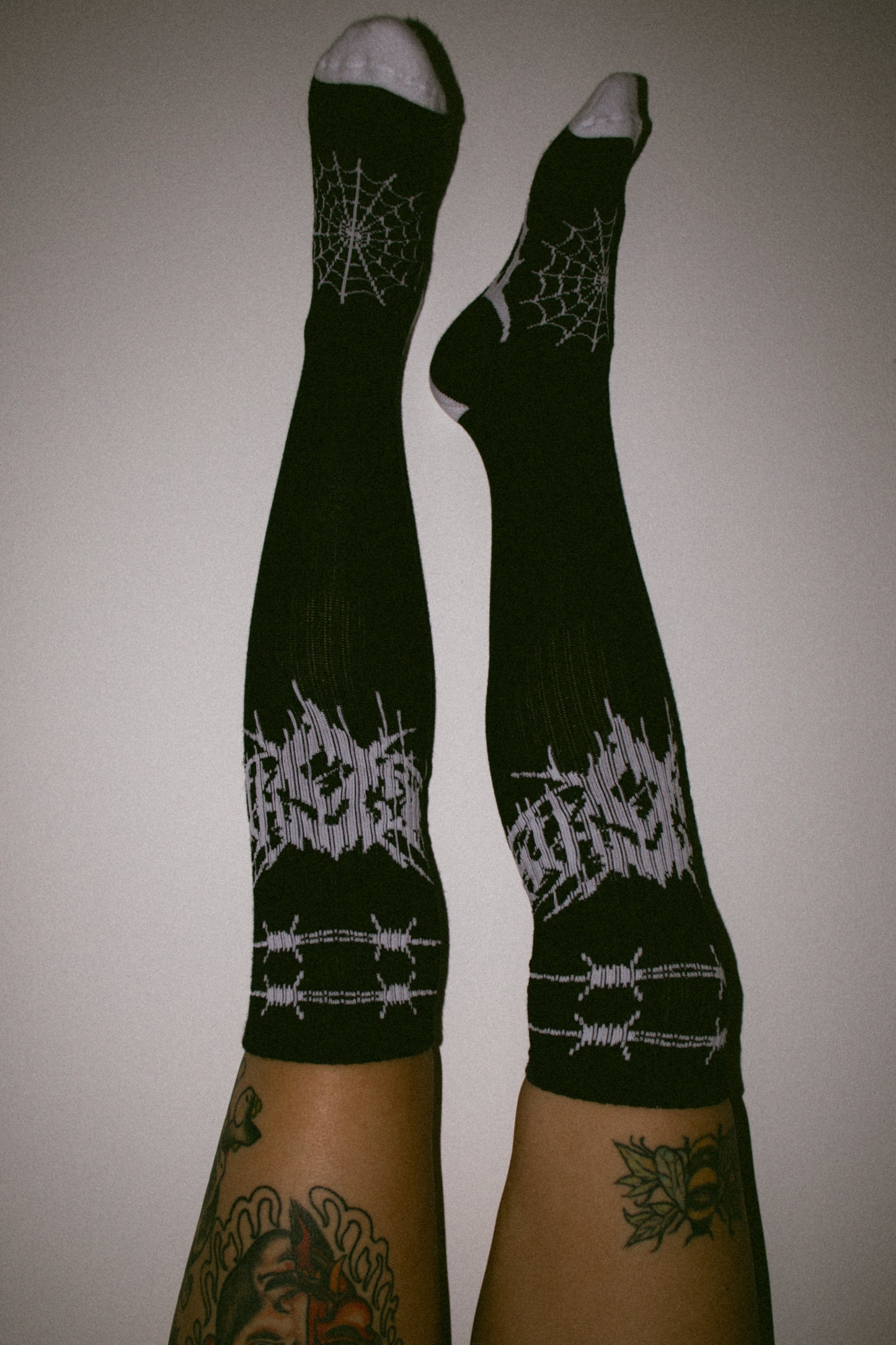 Eightysix og socks collaberation metal knee high socks worn by a tattooed alternative lifestyle model