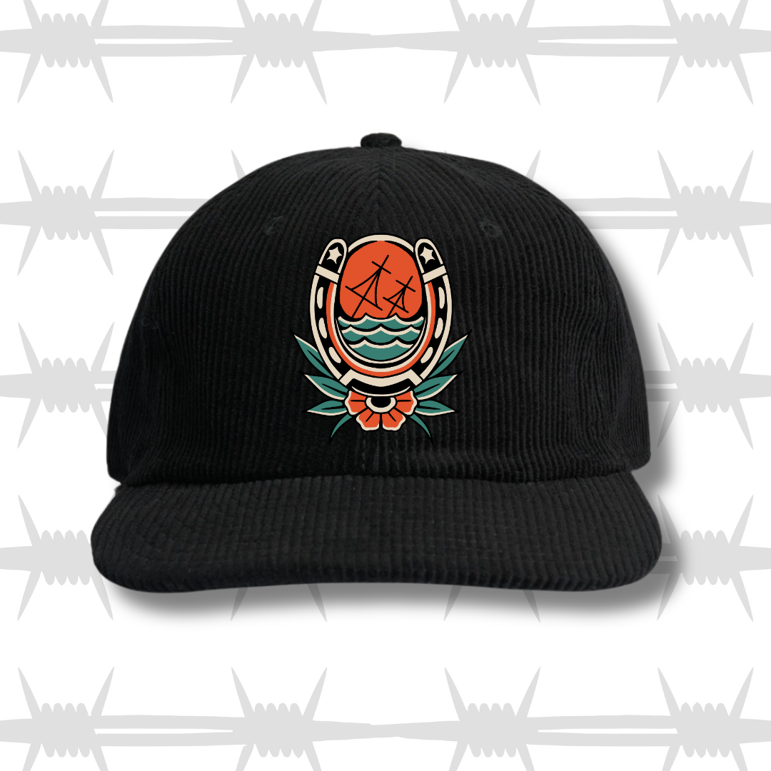 Cord cap in black with traditional tattoo style horse shoe with sinking ship and flower