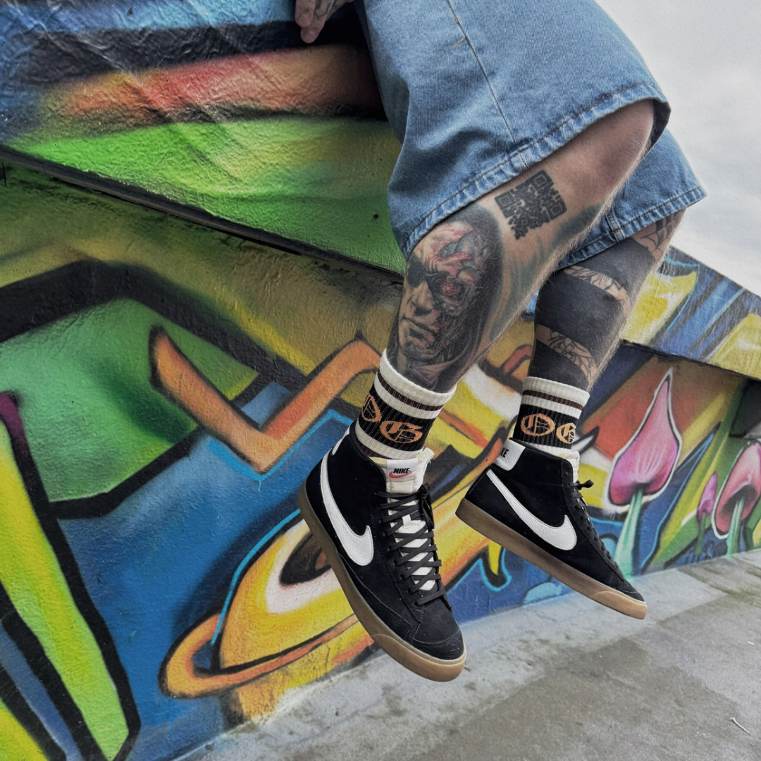 White OG socks with two espresso stripes and a black band with an orange OG logo worn by tattooed model