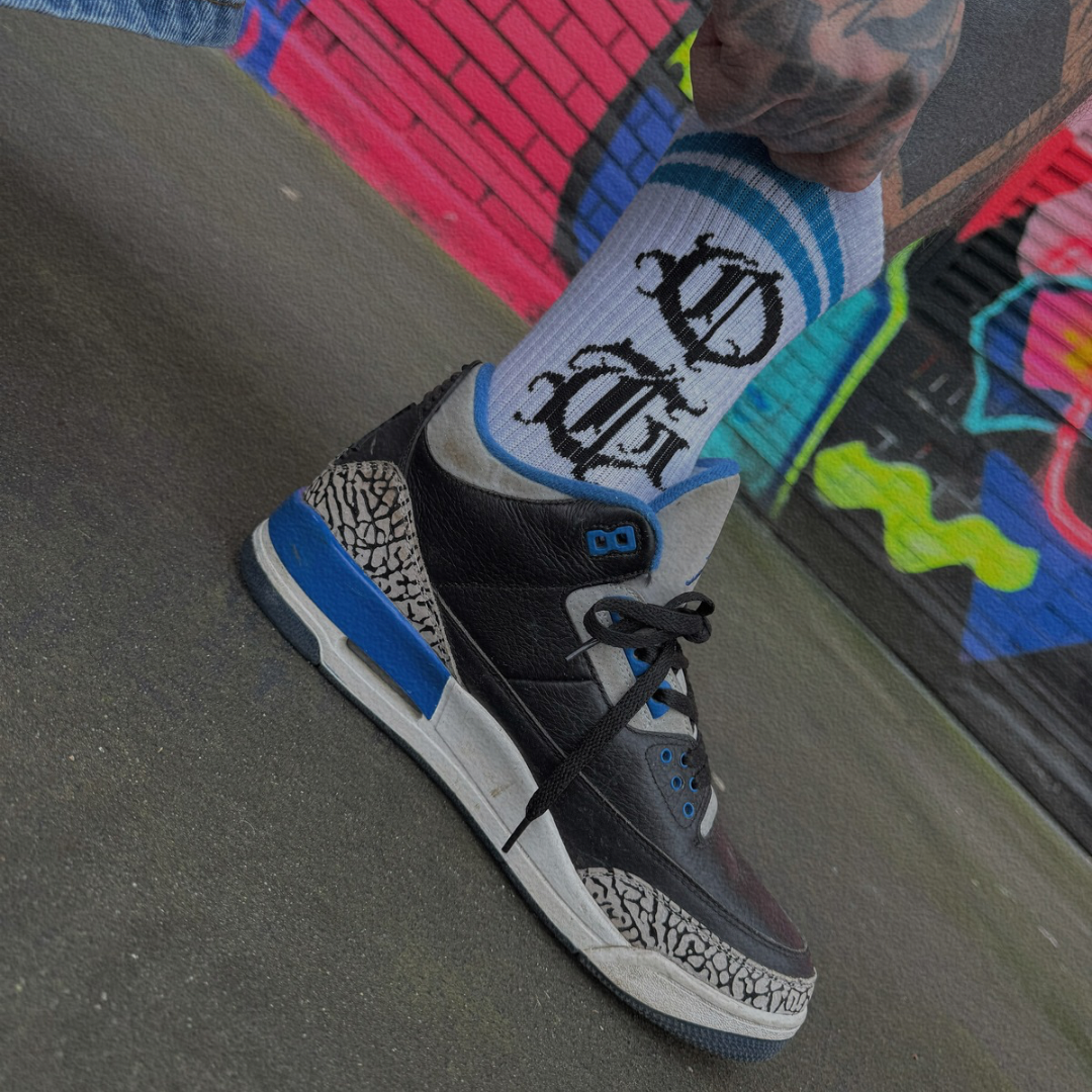 White og sock with two blue stripes and OG logo written in old english worn by model