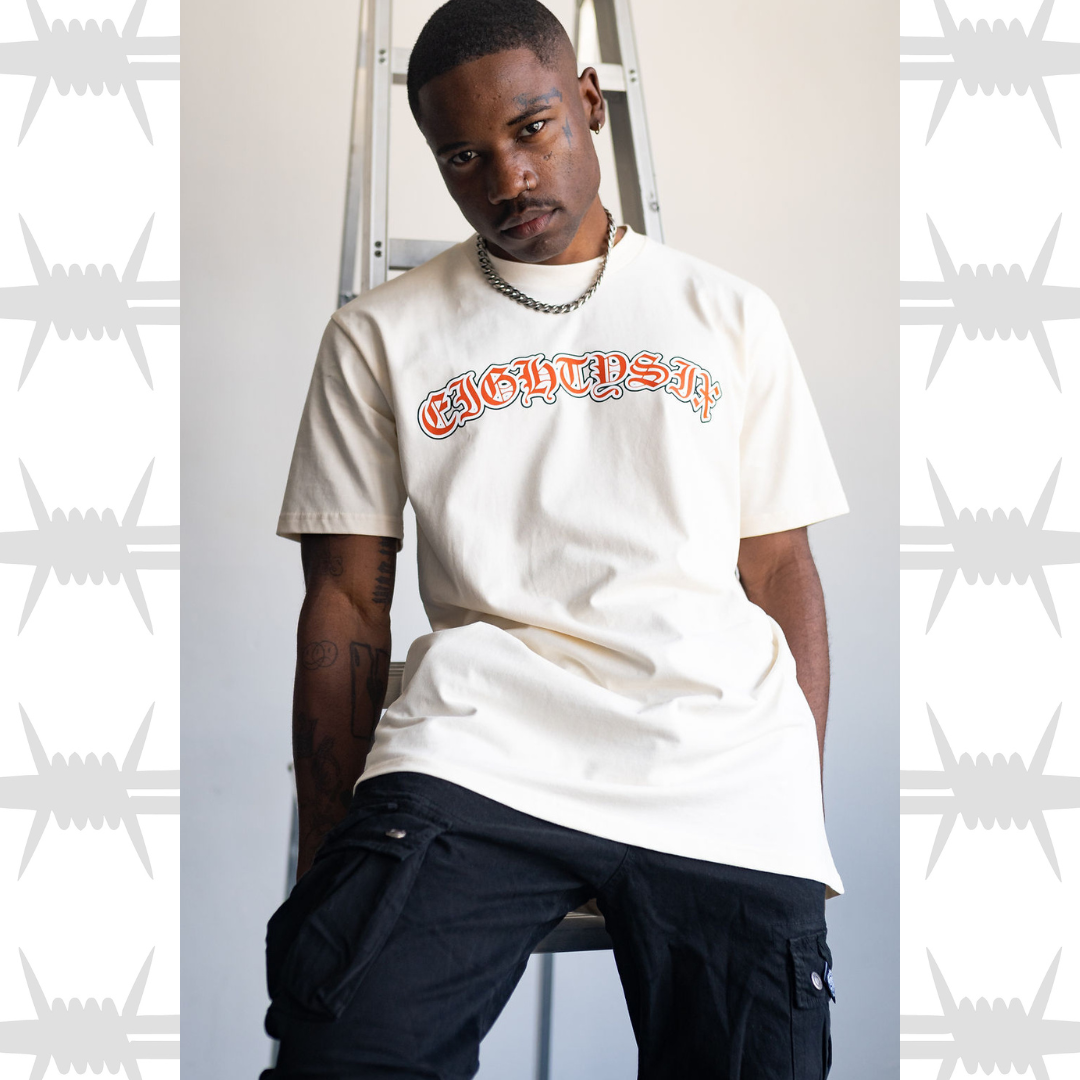 Old English Script t-shirt featuring eightysix logo in old english tattoo font, worn by tattooed alternative model