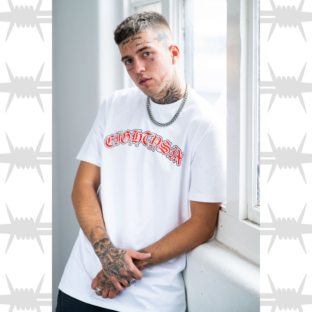 Old English Tattoo script t-shirt in white with orange script, worn by alternative tattooed model