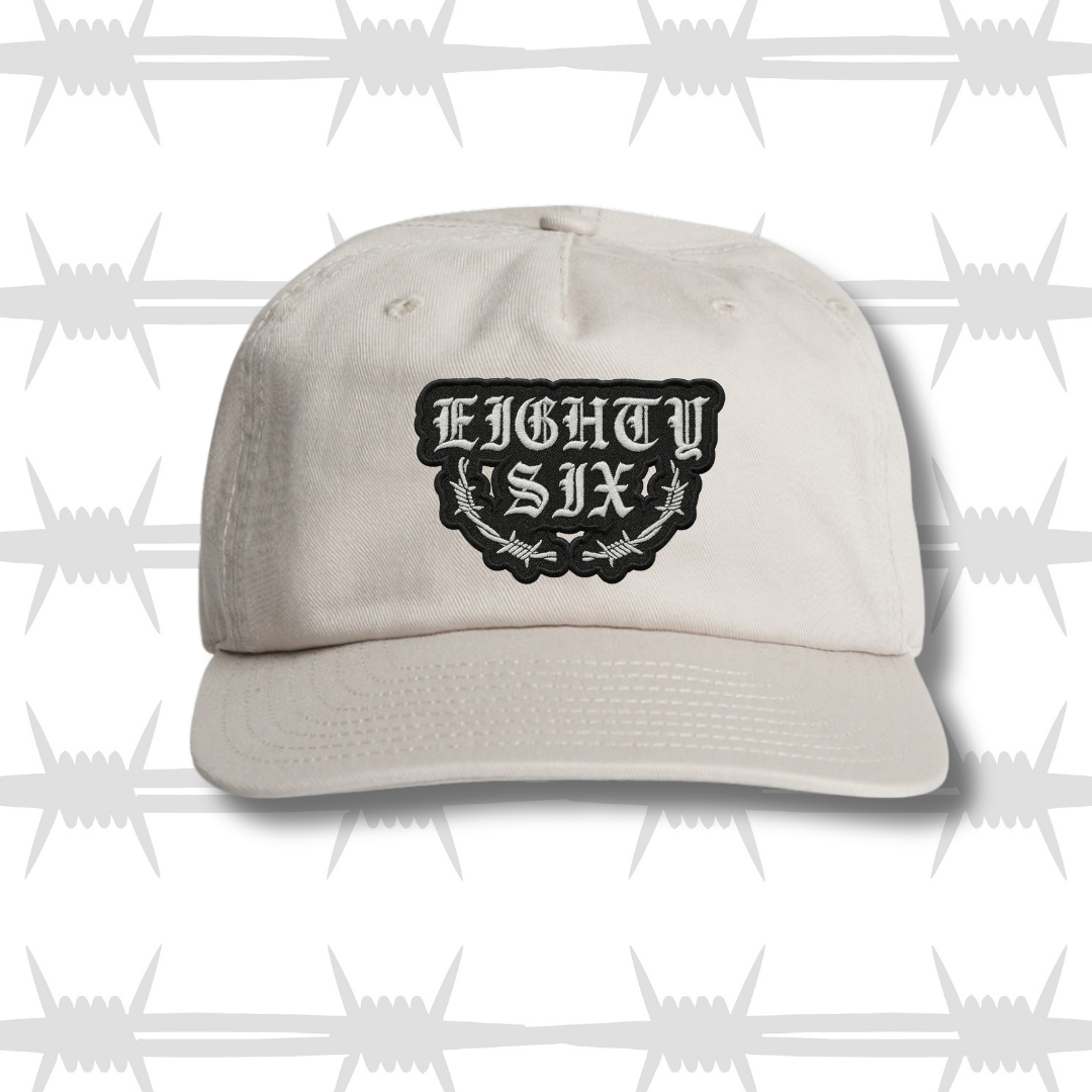 White baseball cap with black embroidered eightysix logo with a barbed wire accent and a tattoo style built to last script front shot