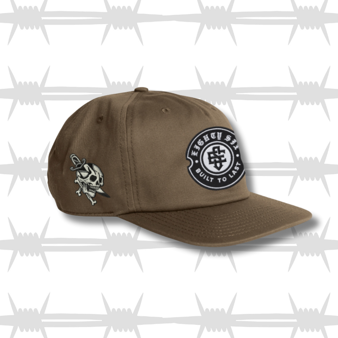 Brown work cap with embroidered crest eightysix logo and skull and dagger tattoo design side profile