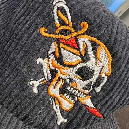 Dagger skull cord cap close up image showing the embroidered traditional tattoo style skull with a dagger