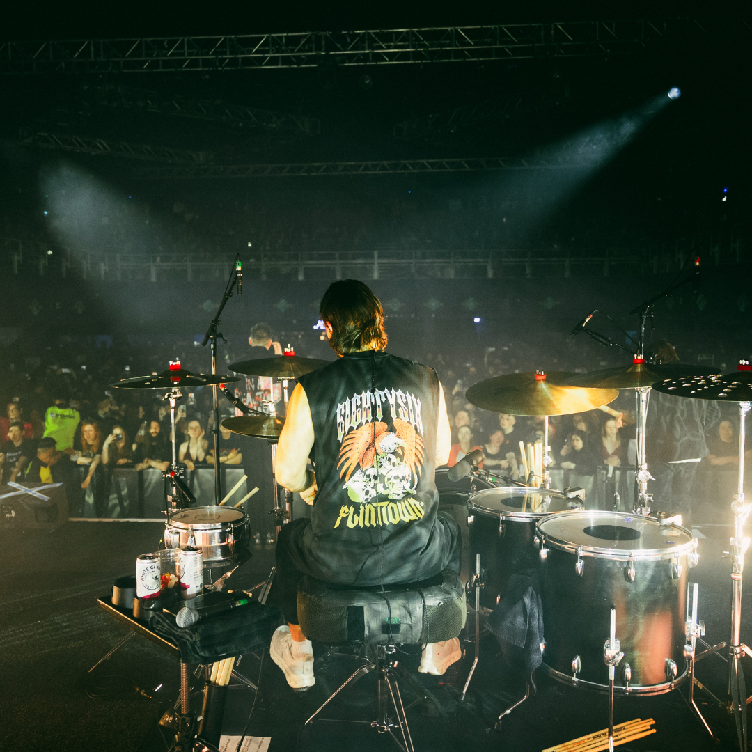 eightysix x flinttown tank from the back worn by the drumer from the band you me at six while playing drums at a live gig