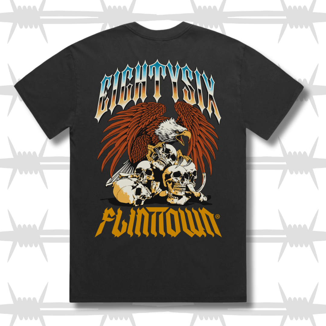 Eightysix X Flinttown t-shirt rear shot, shows eightysixlogo in a chrome tattoo style with an eagle protecting skulls in a tattoo style then the flinttown logo in orange below it.