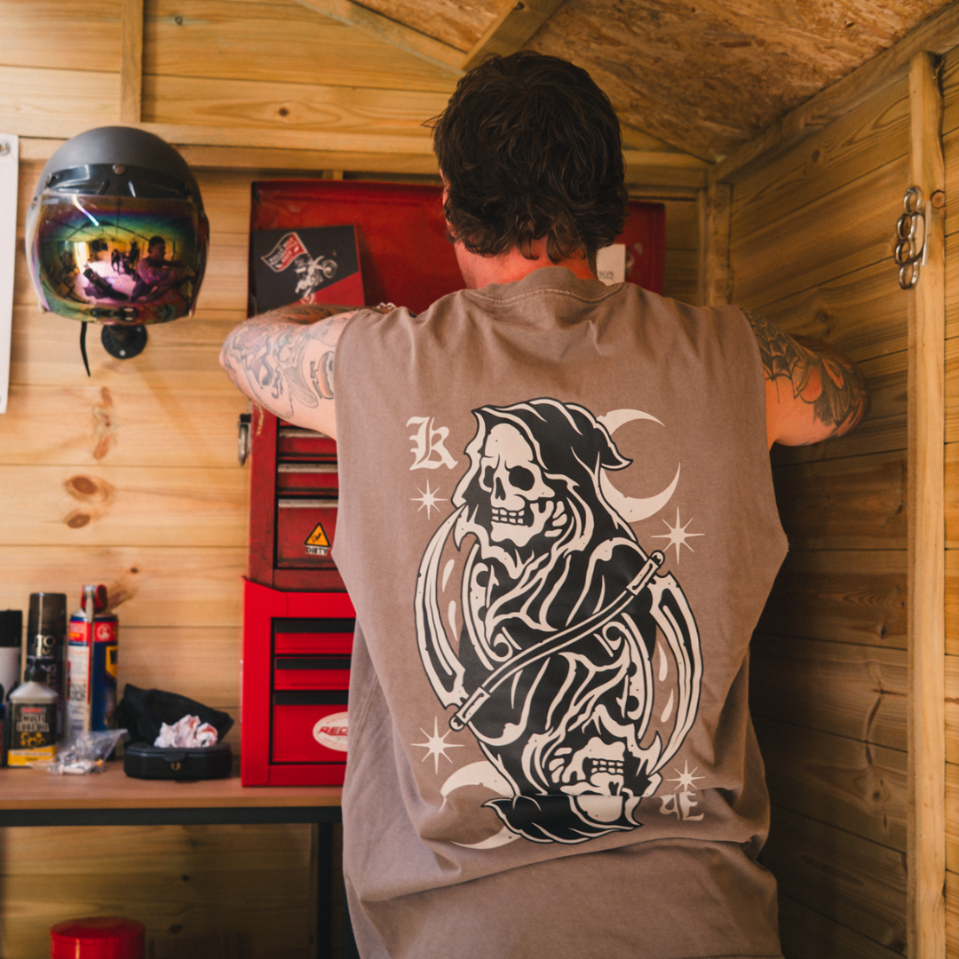 Model wearing tank top with tattoo inspired reaper design on the back, while in a workshop