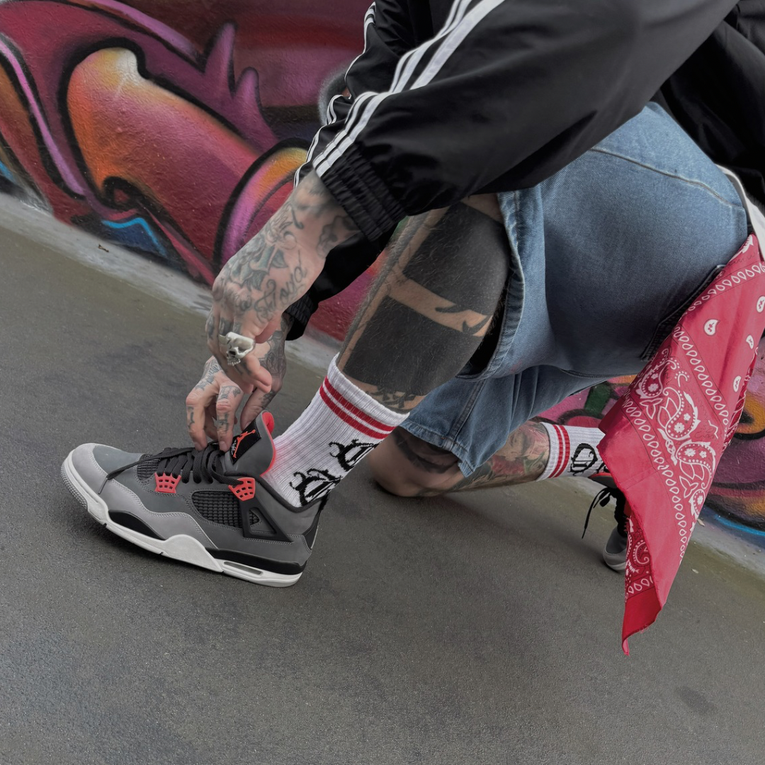 White OG socks with OG writen in old english and two red stripes worn by streetwear model