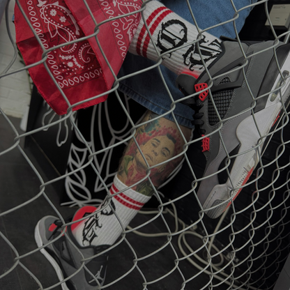 White OG socks with OG writen in old english and two red stripes worn by tattooed model