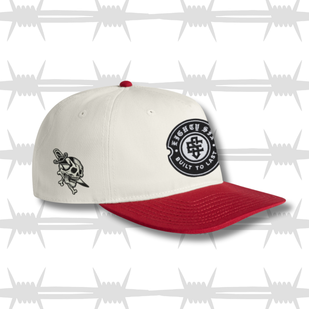 White and Red two tone cap with black embroidered tattoo inspired skull and dagger design and built to last crest logo