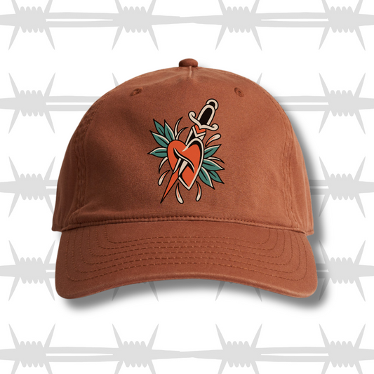 Clay colour dad cap with traditional tattoo style heart and dagger design
