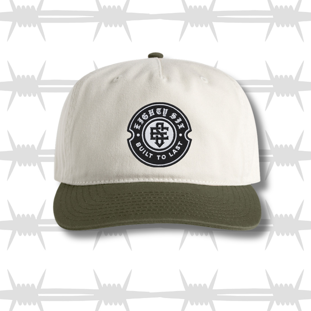 White and green two tone cap with black embroidered tattoo inspired skull and dagger design and built to last crest logo